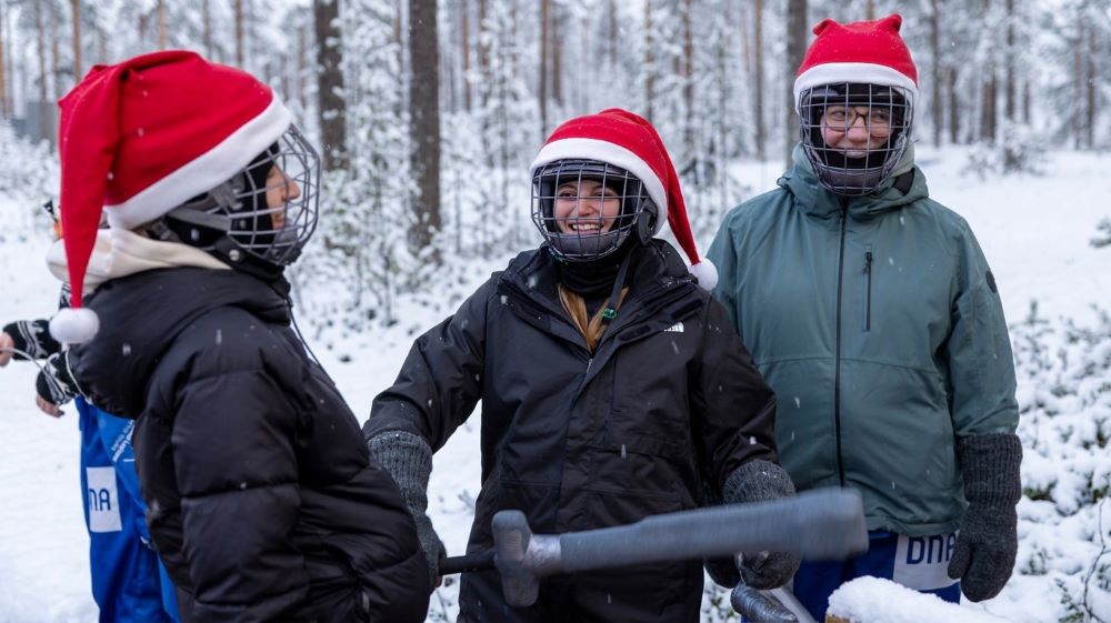 Three laughing recruits in helmets and Santa hats holding padded weapons